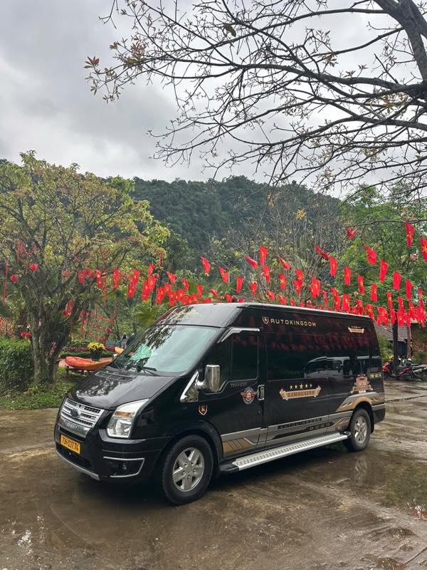 Xe limousine Ford Transit màu đen đỗ cạnh hàng cờ lễ hội